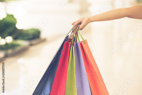 Woman hand holding colorful shopping bags on blurry background