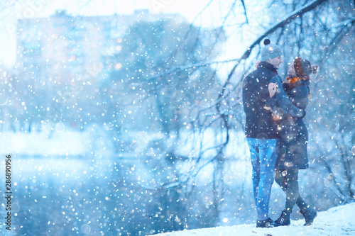 young man and woman in the snow in a city park couple winter