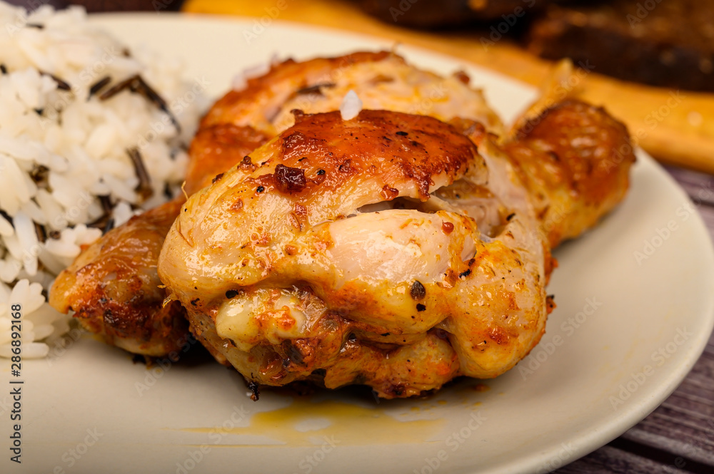 Chicken legs with spices fried in a cauldron, Served on a plate with rice Chicken legs with spices fried in a cauldron, Served on a plate with rice