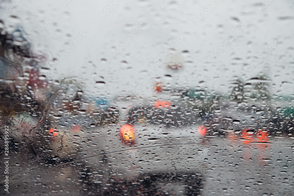 Drops Of Rain Drizzle on the glass windshield in the evening. street in the heavy rain. Bokeh Tail light and Traffic lights in city. Please drive car carefully, slippery road. soft focus. Drops Of Rain Drizzle on the glass windshield in the evening. street in the heavy rain. Bokeh Tail light and Traffic lights in city. Please drive car carefully, slippery road. soft focus.