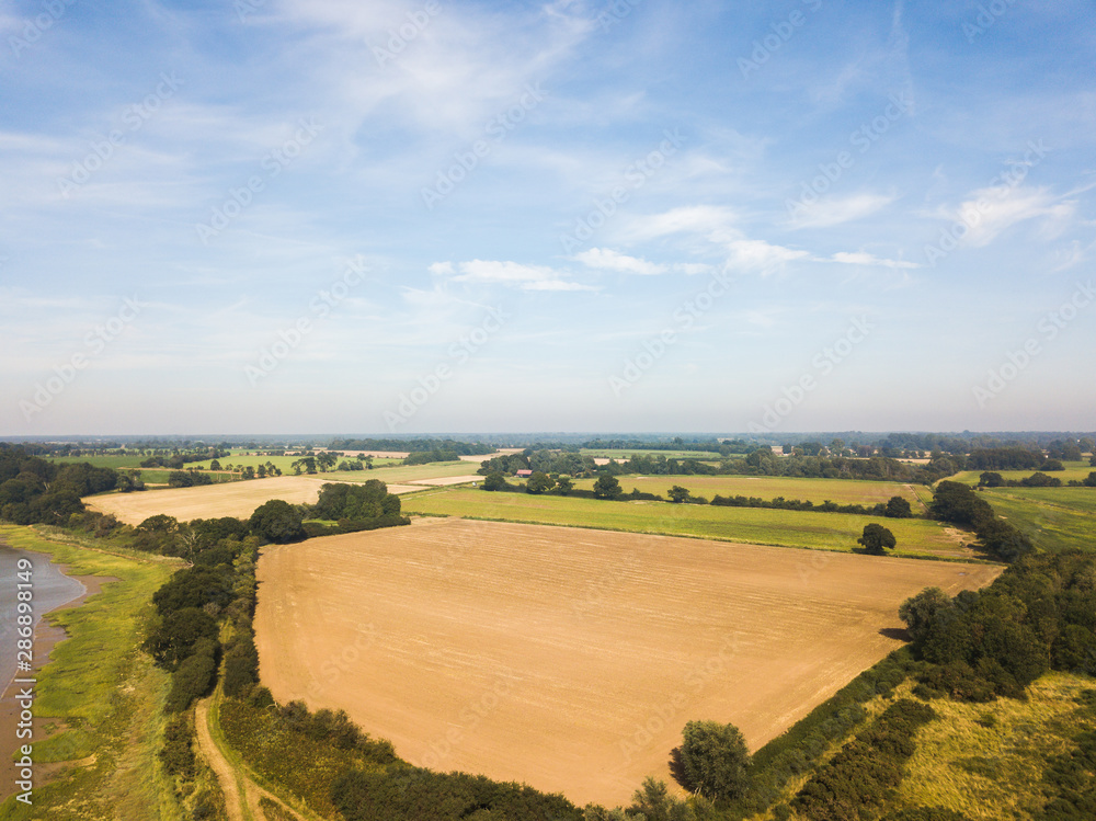 Aerial view of the Suffolk countryside with a recently harvested hay field in the foreground