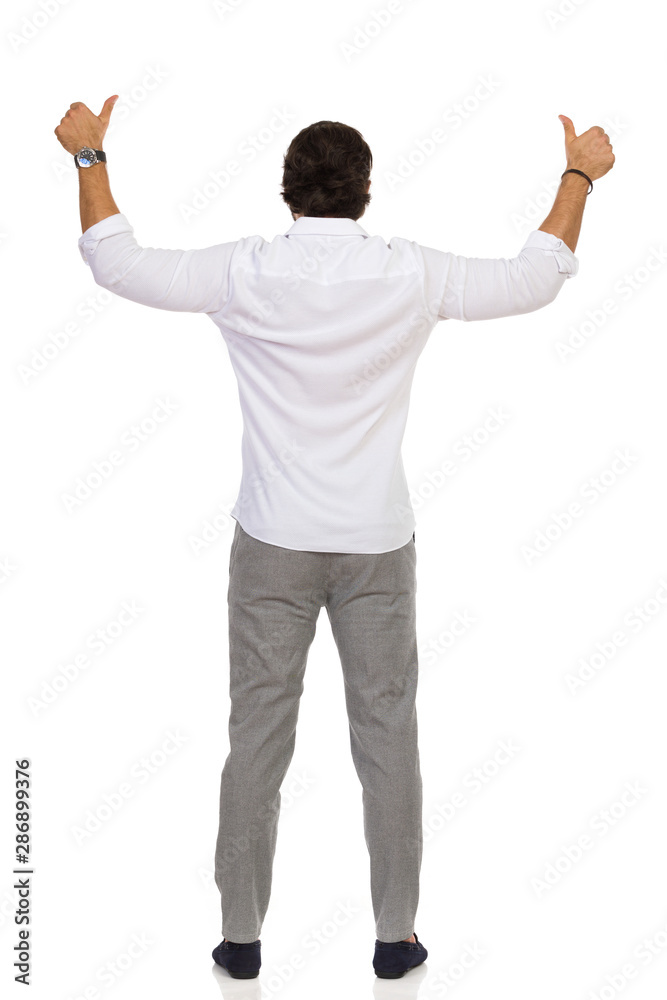 Elegant Man In Gray Trousers And White Shirt Is Standing And Showing Thumbs Up. Rear View.