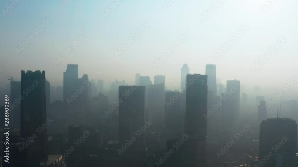 JAKARTA, Indonesia - August 27, 2019: Aerial view of dense air pollution smog and silhouette of modern office buildings on the morning. Shot in 4k resolution from a drone flying upwards JAKARTA, Indonesia - August 27, 2019: Aerial view of dense air pollution smog and silhouette of modern office buildings on the morning. Shot in 4k resolution from a drone flying upwards