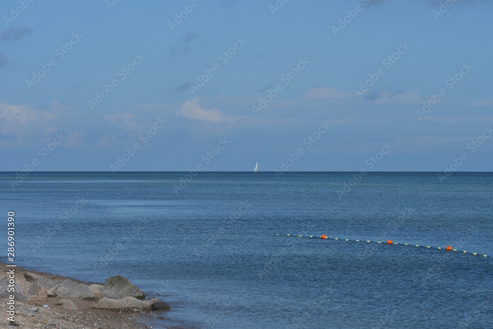 Bewegte blaue See mit weißem Segelschiff am Horizont