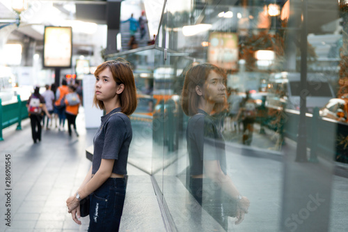 Asian woman standing leaning on glass in the city lonely looking something,bright concept