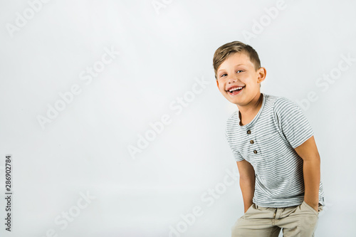 Little boy with autism standing on a white background feeling happy and smiling