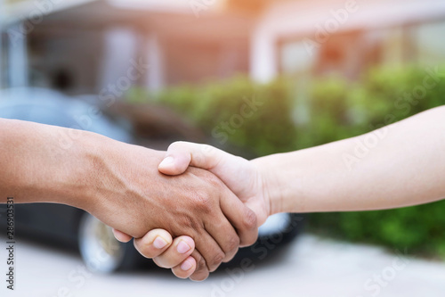 auto business. Close up of a business man dealer offer car to new owner and hand shake between two congratulations to customers. filter tone outdoor sunny in the morning. office background. © methaphum