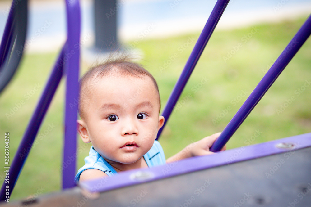 Little Adorable baby boy climbing slider's stair in playground