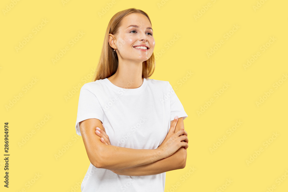 Caucasian young woman's half-length portrait on yellow studio background. Beautiful female model in white shirt. Concept of human emotions, facial expression, sales. Standing hands crossed, confident. Caucasian young woman's half-length portrait on yellow studio background. Beautiful female model in white shirt. Concept of human emotions, facial expression, sales. Standing hands crossed, confident.
