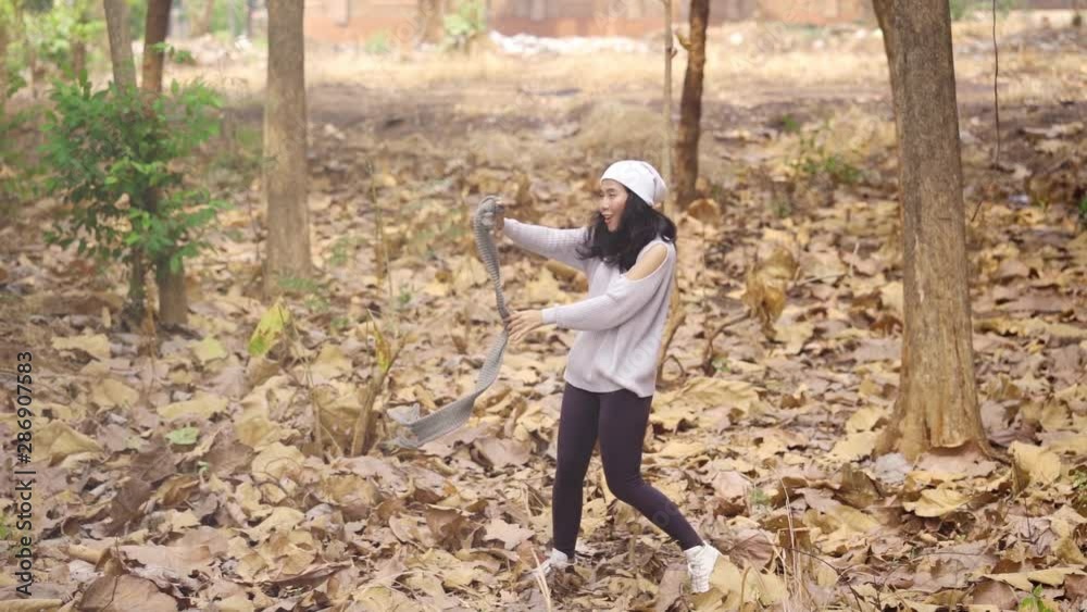 Slow motion of joyful young woman dancing and the autumn park while holding a knitted scarf. Shot outdoors Slow motion of joyful young woman dancing and the autumn park while holding a knitted scarf. Shot outdoors