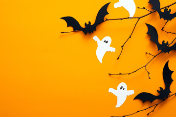 Happy halloween holiday concept. Halloween decorations, bats, ghosts on orange background. Halloween party greeting card mockup with copy space. Flat lay, top view, overhead.