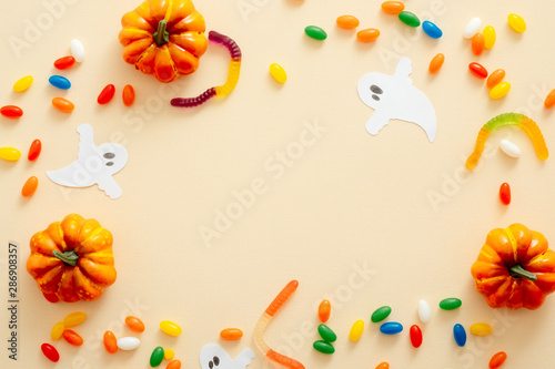 Fototapeta Naklejka Na Ścianę i Meble -  Halloween composition. Halloween decorations, pumpkins, candy on pastel beige background. Halloween concept. Flat lay, top view, copy space