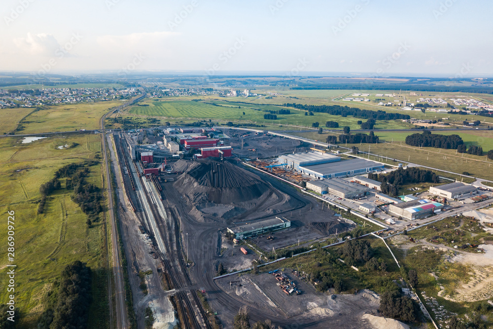 Aerial view of a large plant with mines for the extraction of coal. Mounds of black coal near production and industry.