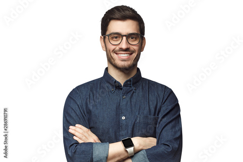 Portrait of young smiling caucasian man with crossed arms, wearing smart watch and casual denim shirt, isolated on white