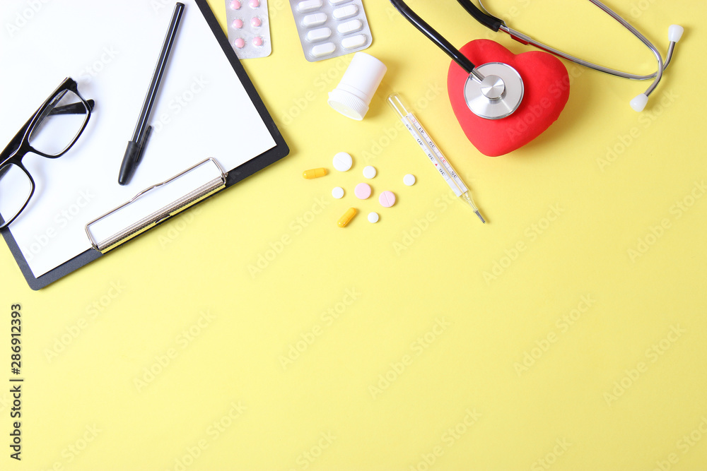 Doctor's desk top view. Stethoscope, pills, glasses and notebook on a colored background. Doctor's desk top view. Stethoscope, pills, glasses and notebook on a colored background.