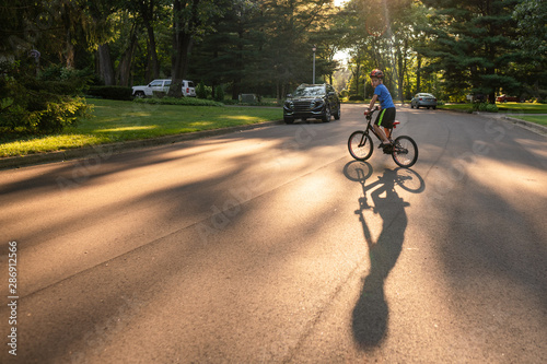 Boy Riding Bike in Neighorhood at Sunset