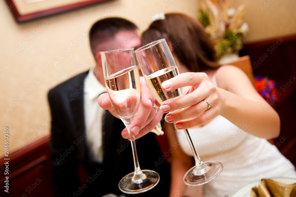 newlyweds pull glasses with champagne forward, covering their faces, kiss newlyweds pull glasses with champagne forward, covering their faces, kiss