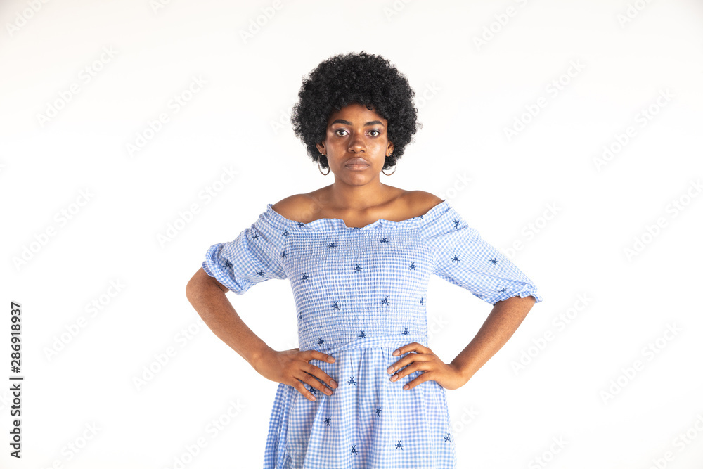 Beautiful female half-length portrait isolated on white studio background. Young emotional african-american woman in blue dress. Facial expression, human emotions concept. Standing and looks confident Beautiful female half-length portrait isolated on white studio background. Young emotional african-american woman in blue dress. Facial expression, human emotions concept. Standing and looks confident