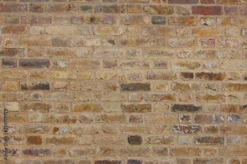 A photograph of old stone brick texture. Pale sand-coloured bricks. Background texture