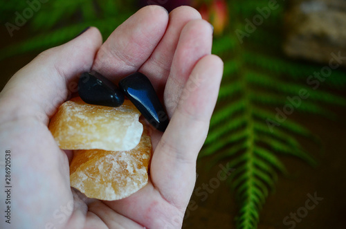 Tumbled Apache Tear and Rough Orange Calcite Duo! Black and Orange, harvest crystals. Witches fall time theme healing crystal bundle. Beautiful, colorful crystal display on wooden table. Natural light