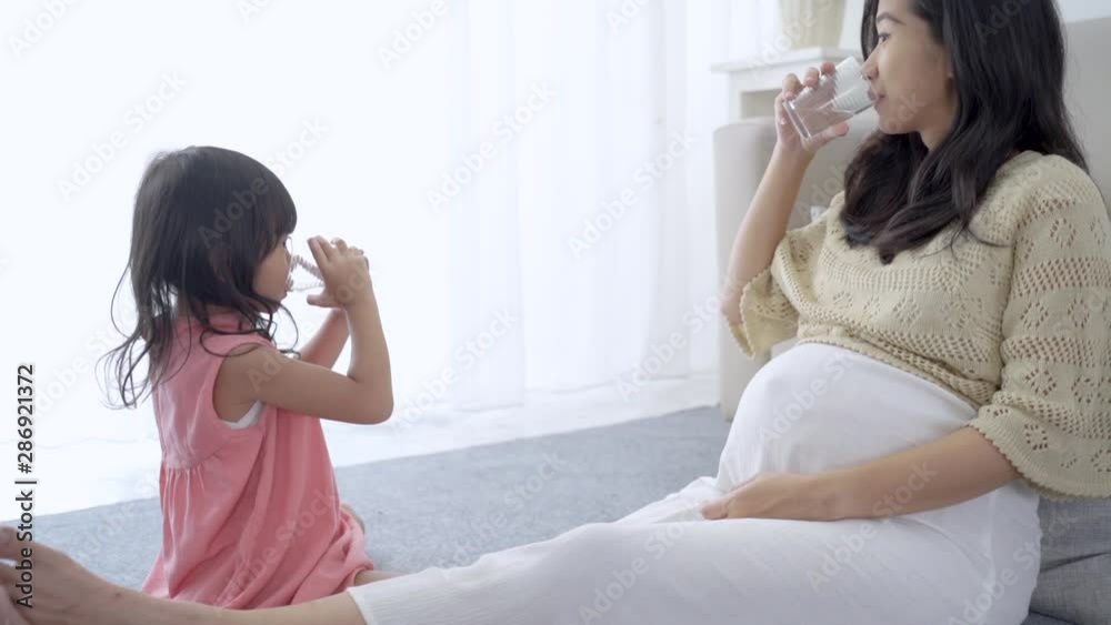 asian mother and daughter drinking water together when sitting on couch asian mother and daughter drinking water together when sitting on couch