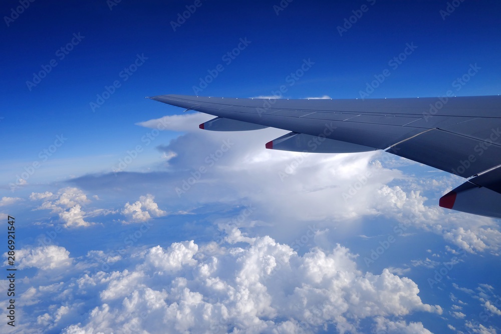A beautiful high view from an airplane window with white fluffy clouds blue sky and a airplane wing A beautiful high view from an airplane window with white fluffy clouds blue sky and a airplane wing