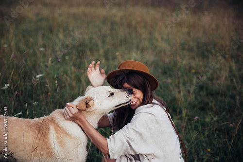 Beautiful young woman relaxed and carefree enjoying a summer sunset with her lovely dog photo