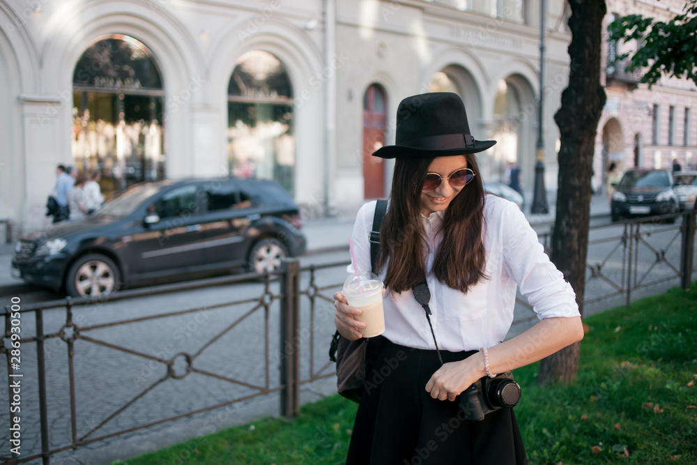Fototapeta premium Young woman in hat walking in city. Girl tourist enjoys the walk.