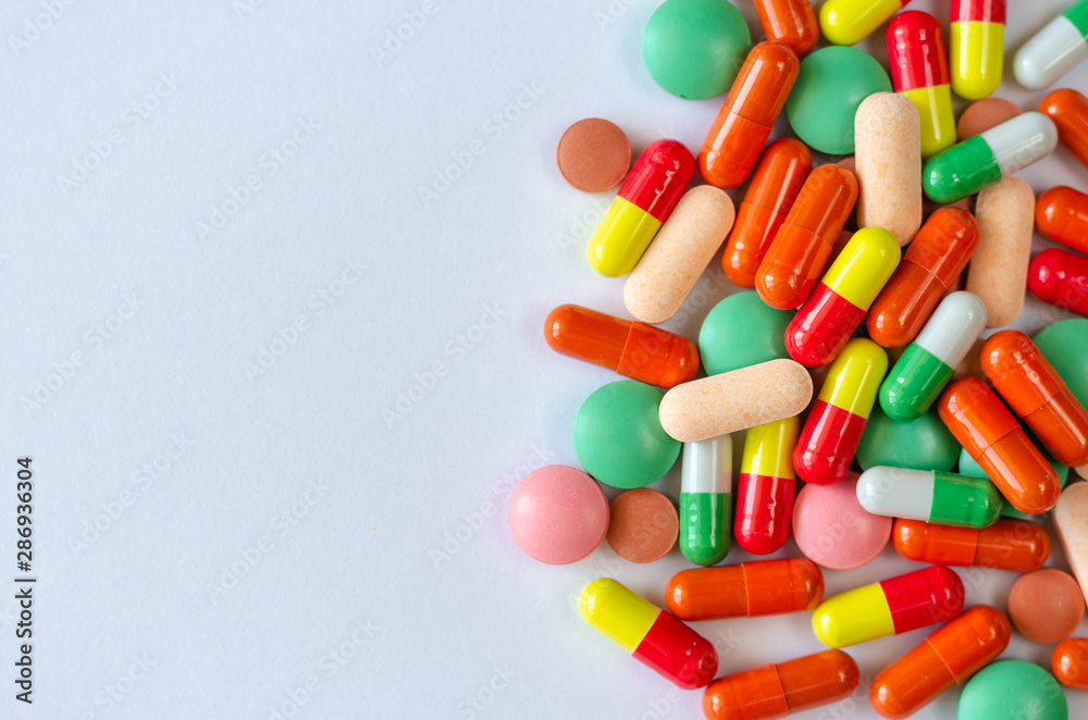 Heap of multi-colored pills, tablets and capsules on a white background. Closeup of medicines. Copy space. Top view Heap of multi-colored pills, tablets and capsules on a white background. Closeup of medicines. Copy space. Top view