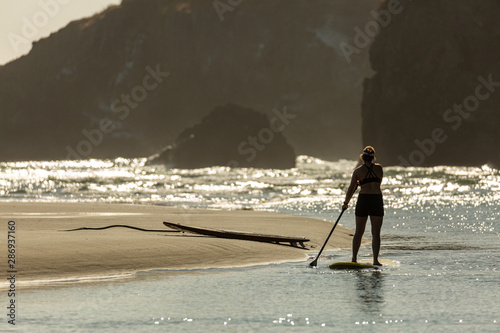 Woman on stand up paddle board on the rocky coast of Mendocino