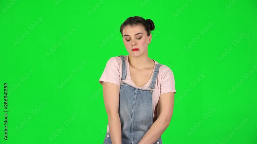 Girl looks upset at the camera and bites her lips green screen at studio. Girl looks upset at the camera and bites her lips green screen at studio.