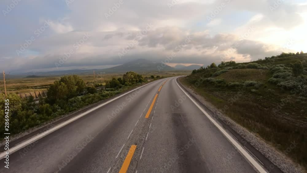 Driving a Car on a Road in Norway at dawn Driving a Car on a Road in Norway at dawn