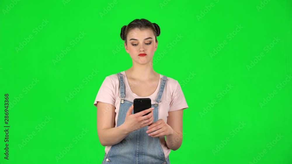 Girl makes selfie on mobile phone then looking photos on green screen Girl makes selfie on mobile phone then looking photos on green screen