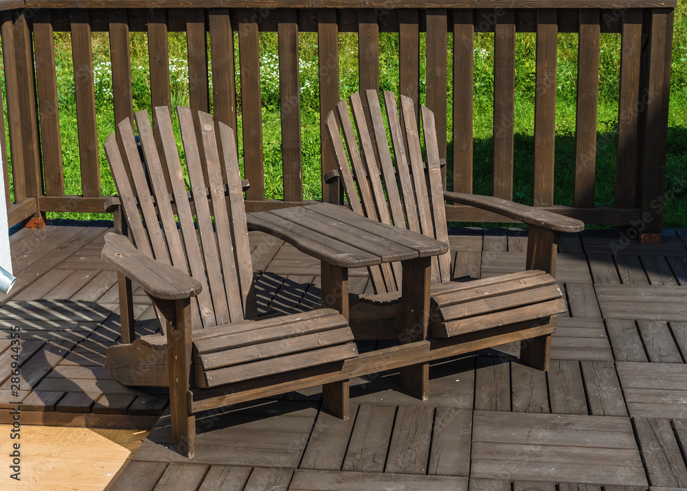 Two wooden chairs stand on the background of the fence Two wooden chairs stand on the background of the fence