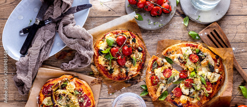 Fresh selfmade mini pizza on rustic wooden oak table 