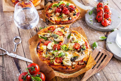 Fresh selfmade mini pizza on rustic wooden oak table 