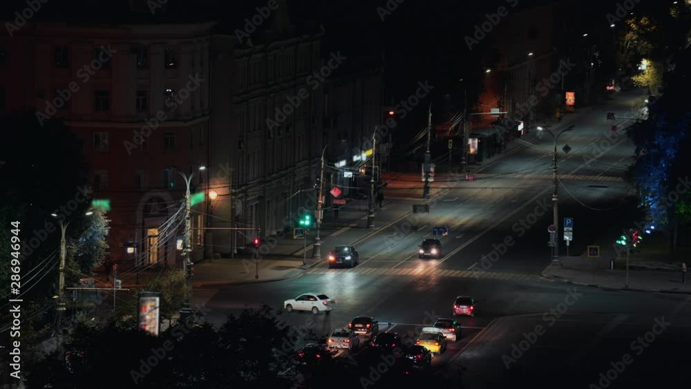 Traffic at lighted intersection or crossroad with traffic light in center or downtown of night European city Traffic at lighted intersection or crossroad with traffic light in center or downtown of night European city
