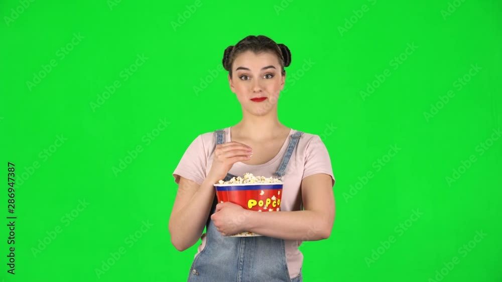 Sweet girl chews popcorn while watching a movie and laughing Sweet girl chews popcorn while watching a movie and laughing