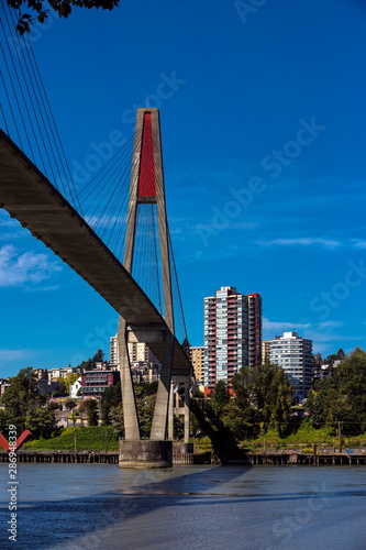 Sky-train bridge linking Surrey and New Westminster over the Fraser River, city on the opposite bank, blue sky with white clouds on a background  photo