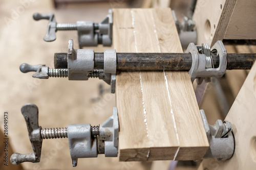 Using clamps and glue to connect wooden timbers for furniture detail. Close up view.