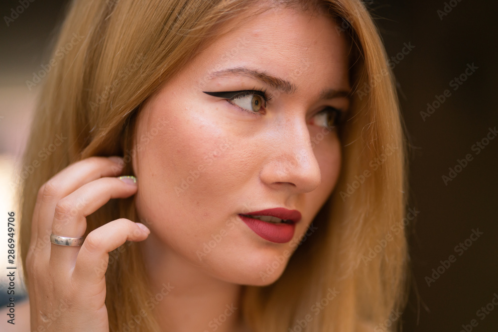 blonde girl with wide make up arrows on the eyes posing in the street blonde girl with wide make up arrows on the eyes posing in the street