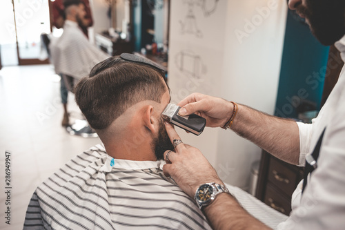 Barber shaves client in barbershop. Barbershop concept 