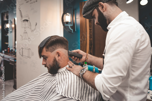 serious bearded guy doing haircut in barbershop. barbershop concept 