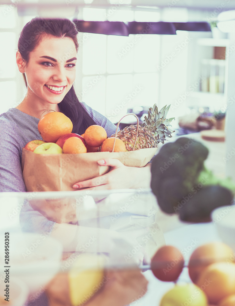 Smiling woman taking a fresh fruit out of the fridge, healthy food concept Smiling woman taking a fresh fruit out of the fridge, healthy food concept