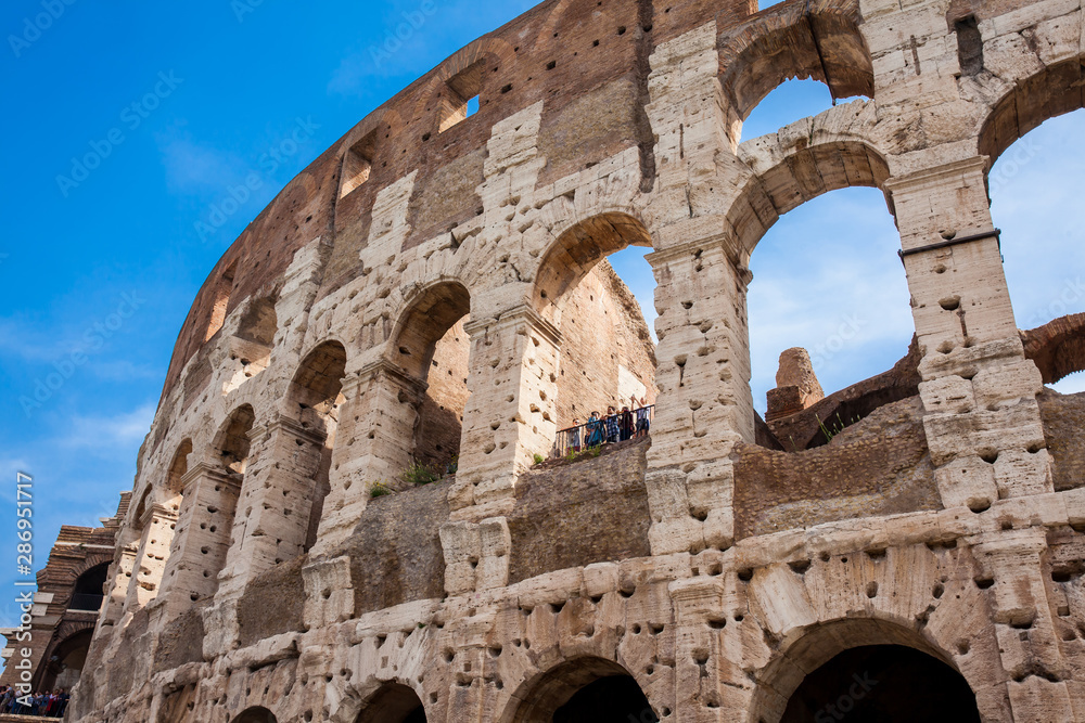 ROME, ITALY - APRIL, 2018: Tourists visiting the famous Colosseum or Coliseum also known as the Flavian Amphitheatre in the centre of the city of Rome