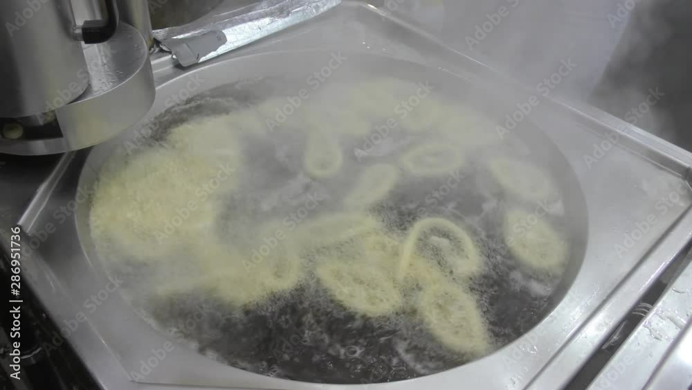 Frying Churros in deep oil in churreria, traditional dough pastry snack