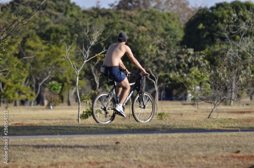 Fototapeta Naklejka Na Ścianę i Meble -  A beautiful view of people walking with bike in Brasilia park, Brazil