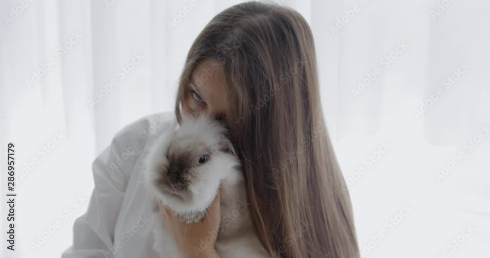 Beautiful caucasian girl holding white bunny. RAW Graded footage 4K slow motion 50fps Beautiful caucasian girl holding white bunny. RAW Graded footage 4K slow motion 50fps