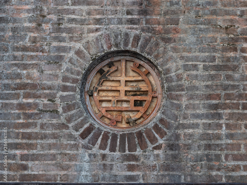 Close Up of Old Metal Medallion in Brick Wall