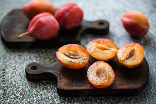 Obraz na plátně Whole and cut ripe plums on a wooden board on a grey table